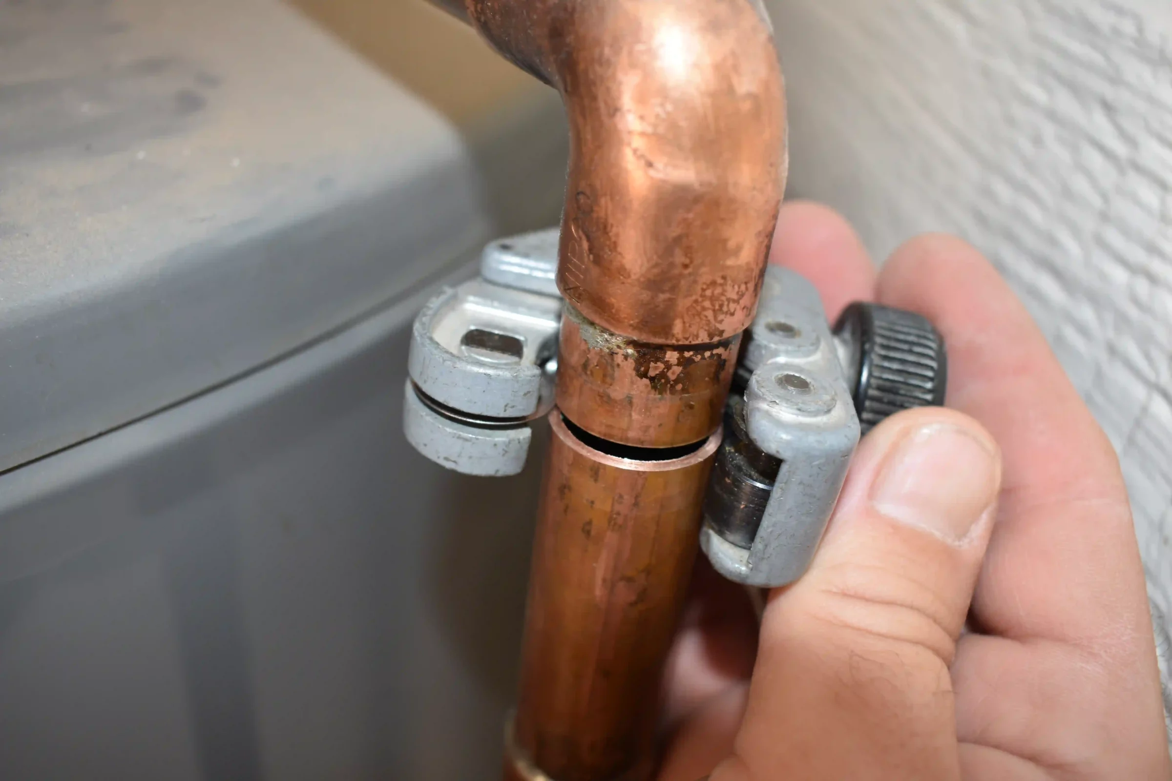 hand with a small tubing cutter, cutting a 1/2